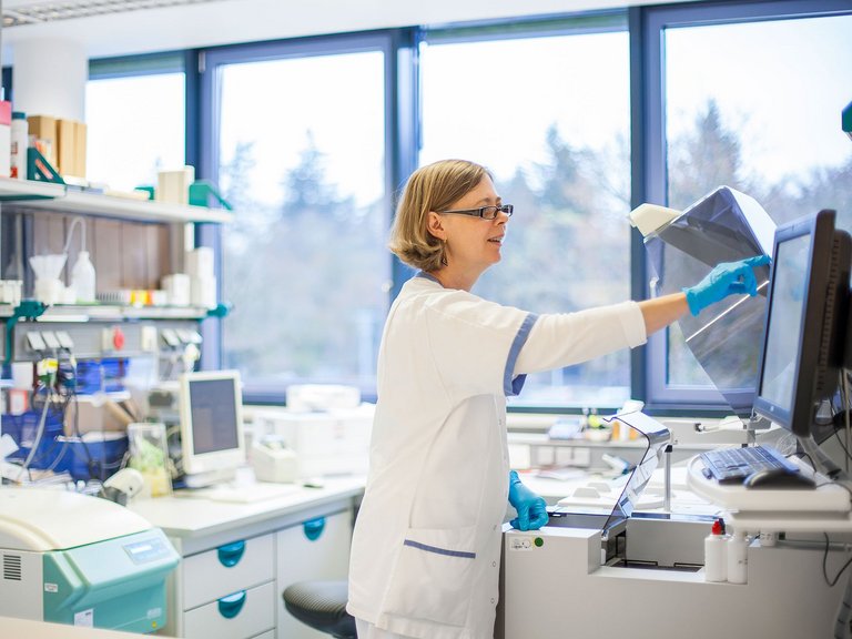 Eine Laborassistentin steht in einem Labor und macht untersuchungen an einem Gerät